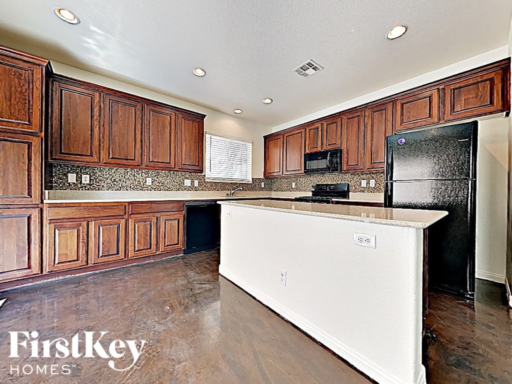 A kitchen with wooden cabinets and a black refrigerator.