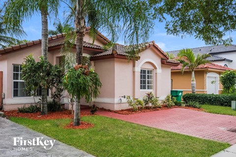 a home with a pink exterior and palm trees