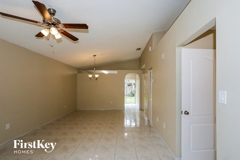 an empty living room with a ceiling fan