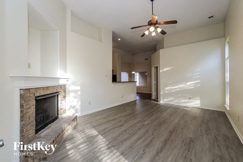 A spacious living room with a fireplace and a ceiling fan.