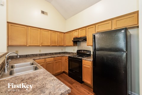 A kitchen with wooden cabinets and a black refrigerator.