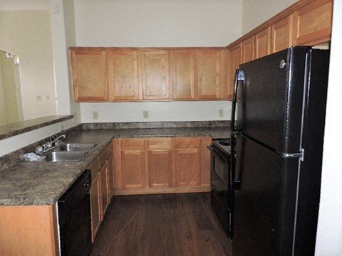 A kitchen with wooden cabinets and a black refrigerator.