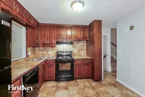 A kitchen with wooden cabinets and a black stove top oven.