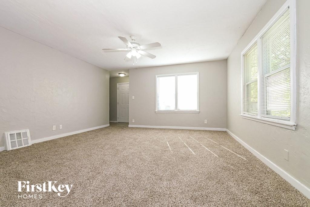A spacious room with a carpeted floor and a ceiling fan.