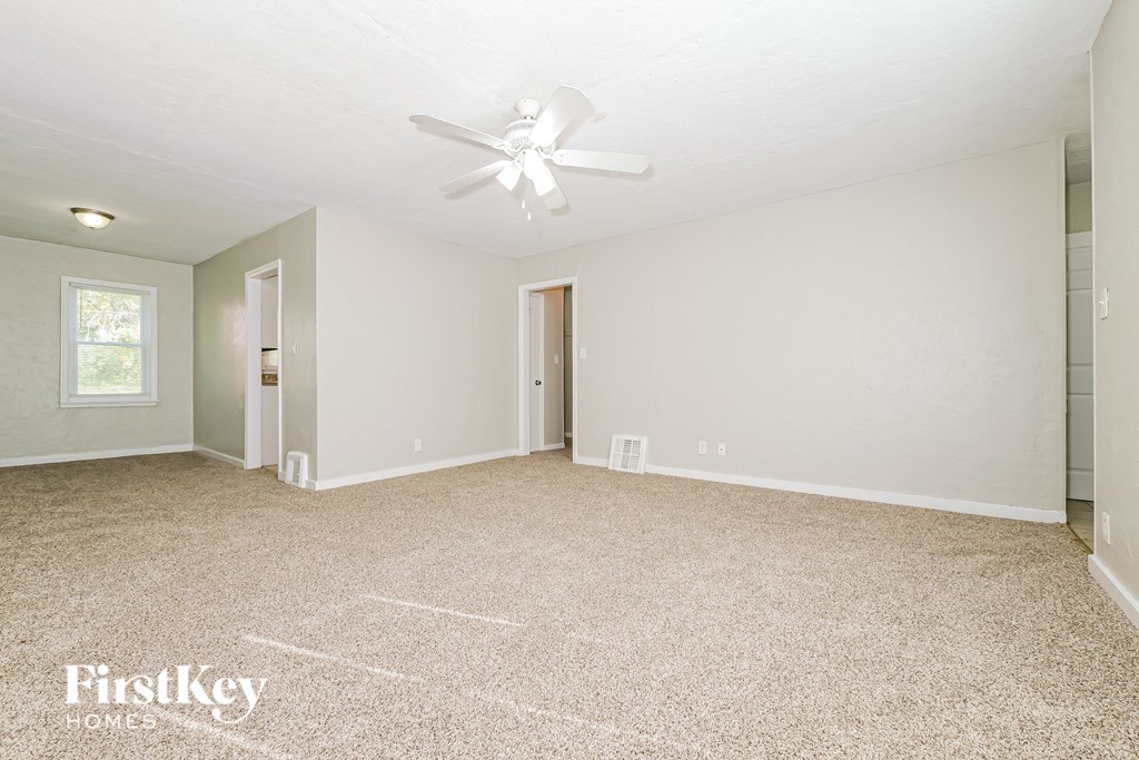 A spacious room with a ceiling fan and a carpeted floor.