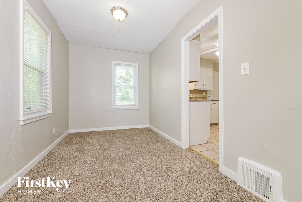 A room with a carpeted floor and a window with blinds.