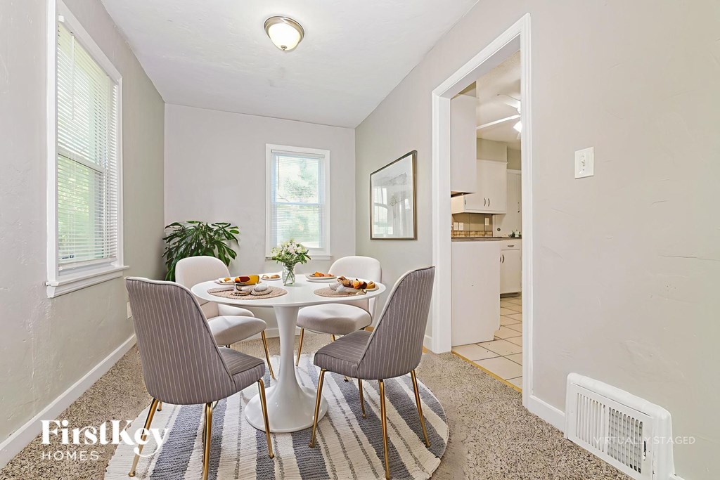 A dining room with a round table and grey chairs.