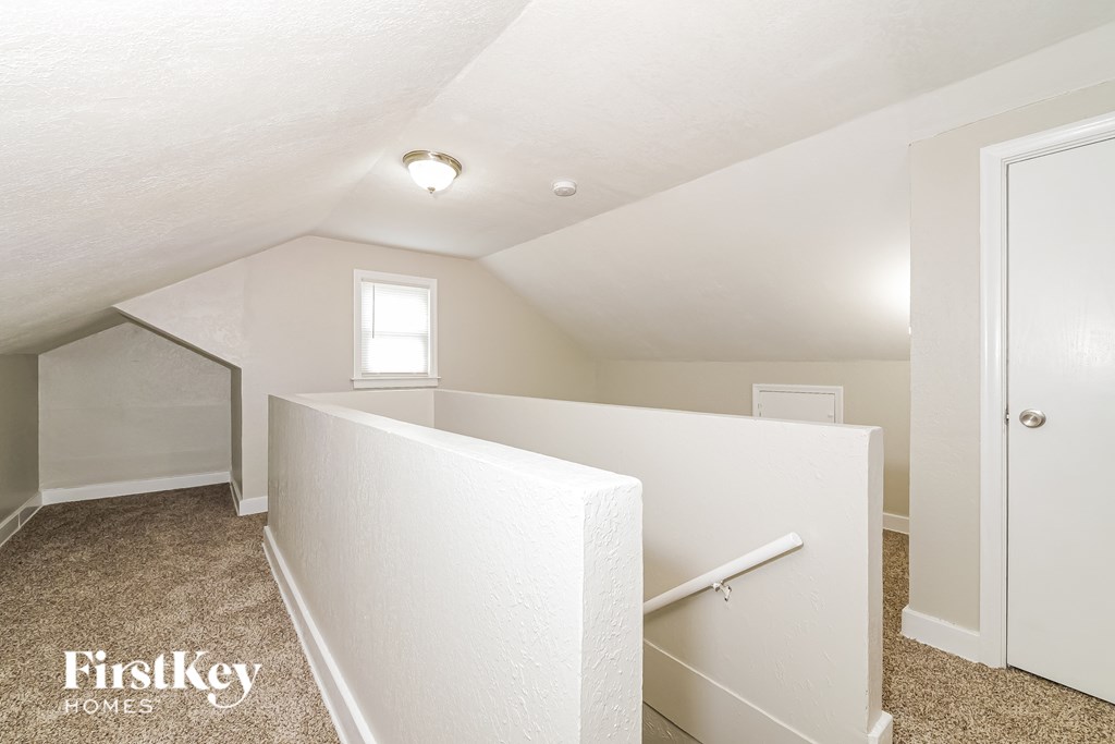 A white bedroom with a window and a door.