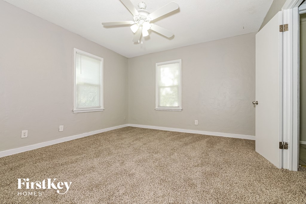 A room with a carpet floor and a ceiling fan.