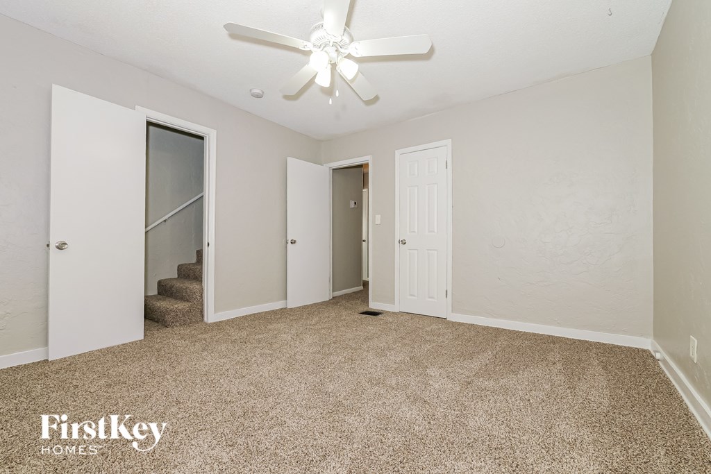 A spacious room with a carpeted floor and a ceiling fan.