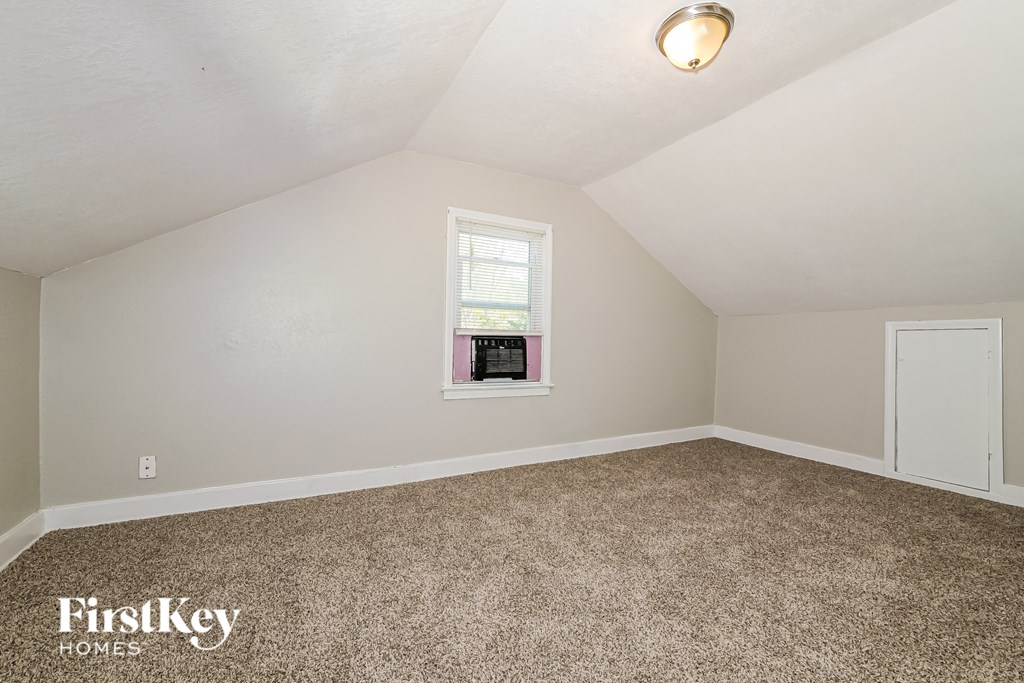 A room with a carpeted floor, a window, and a door.