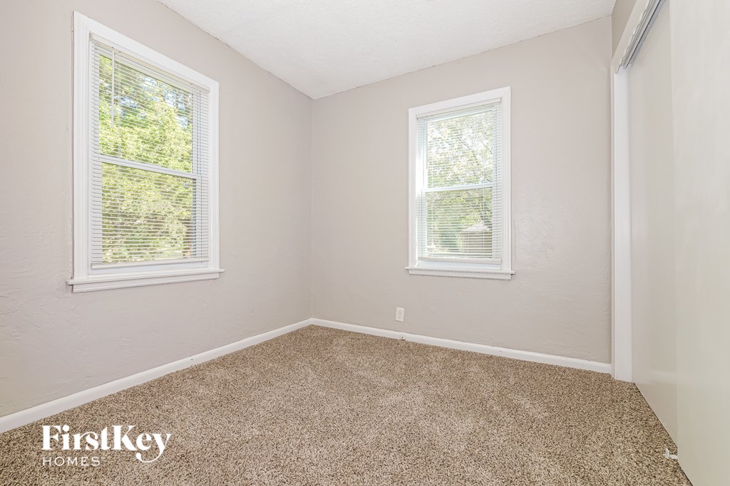 A room with two windows and a carpeted floor.