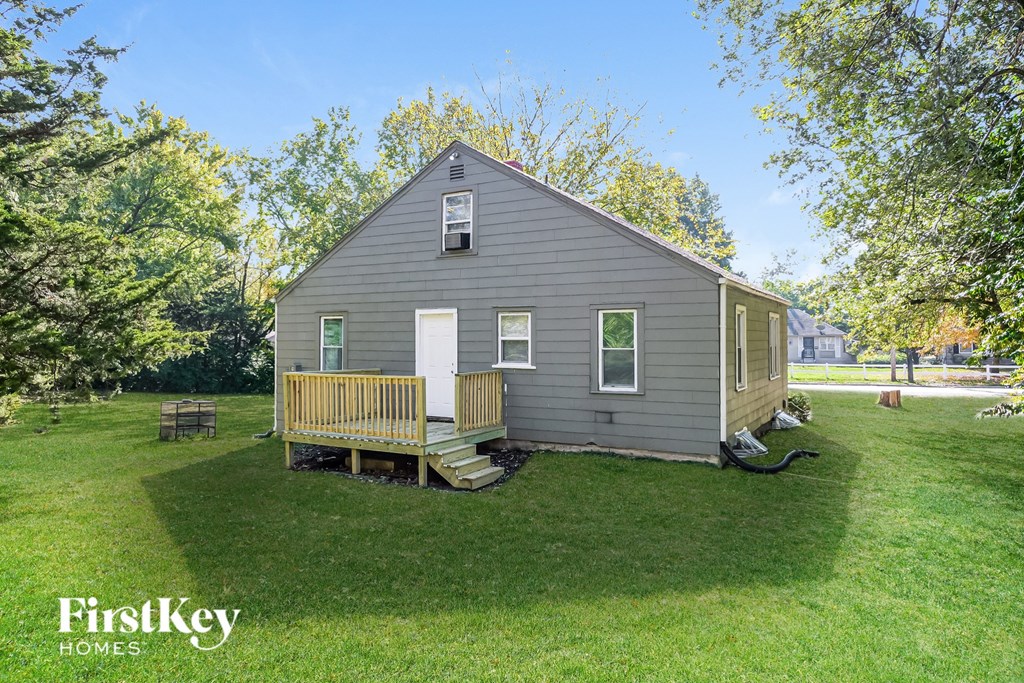 A small house with a porch is surrounded by a grassy yard.