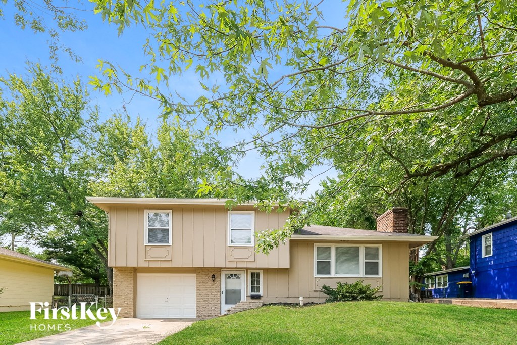 a beige house with a lawn and trees