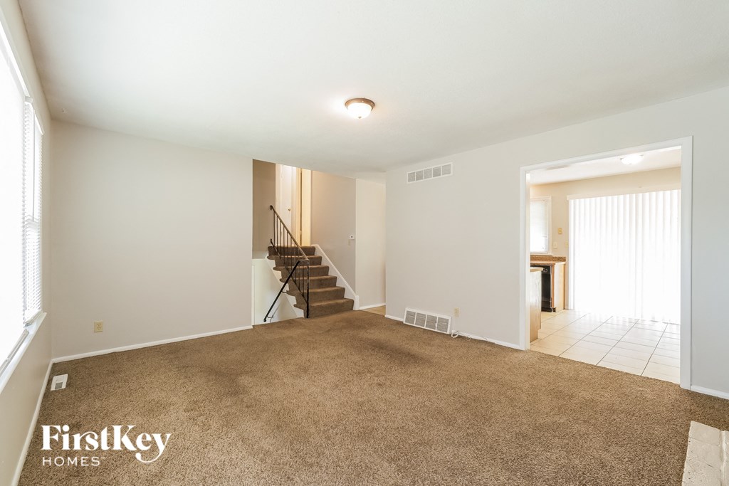 a living room with a carpeted floor and a staircase