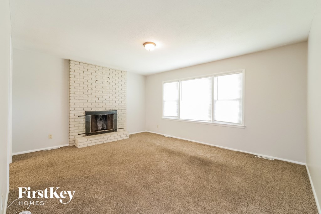 an empty living room with a fireplace and a window