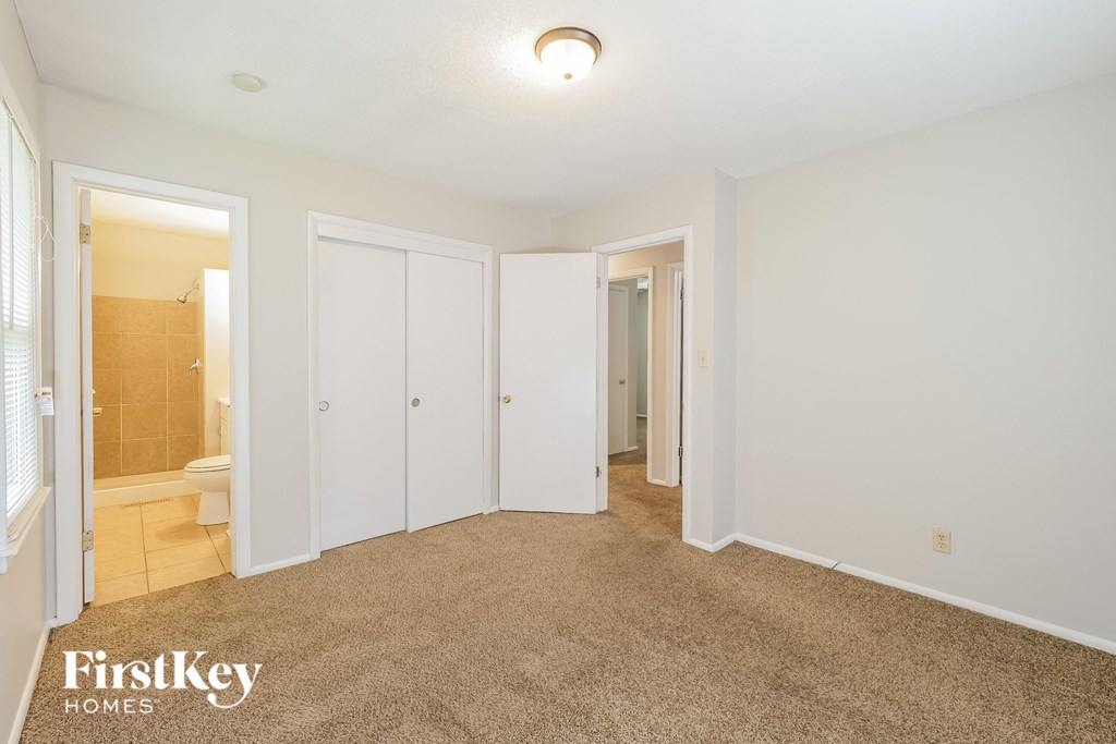 a bedroom with a carpeted floor and a bathroom