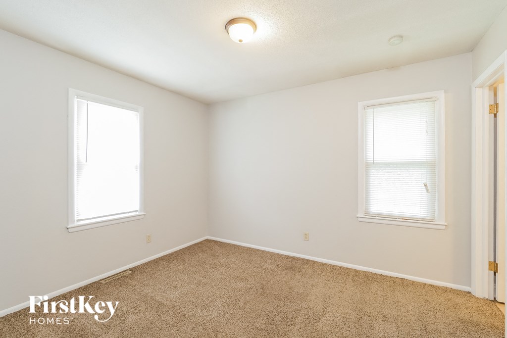 a bedroom with a carpeted floor and two windows