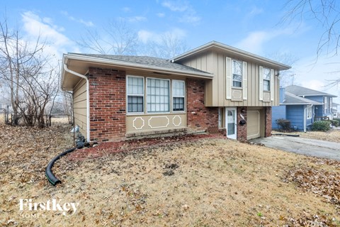 A house with a brick base and beige siding is for sale.