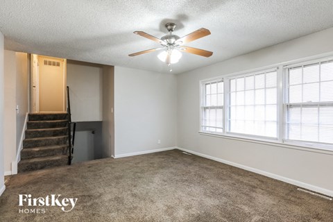 A spacious room with a staircase and a ceiling fan.