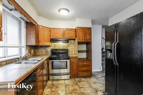 A kitchen with a black refrigerator and brown cabinets.
