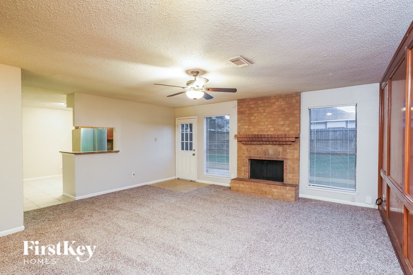 A living room with a fireplace and a ceiling fan.