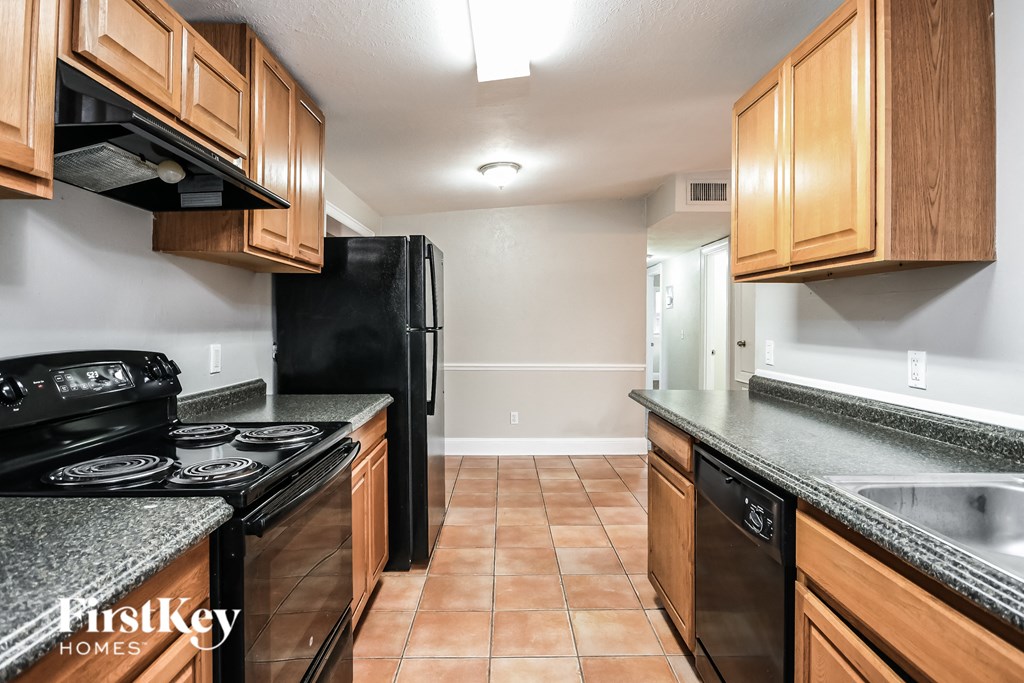 a kitchen with wood cabinets and black appliances and granite counter tops
