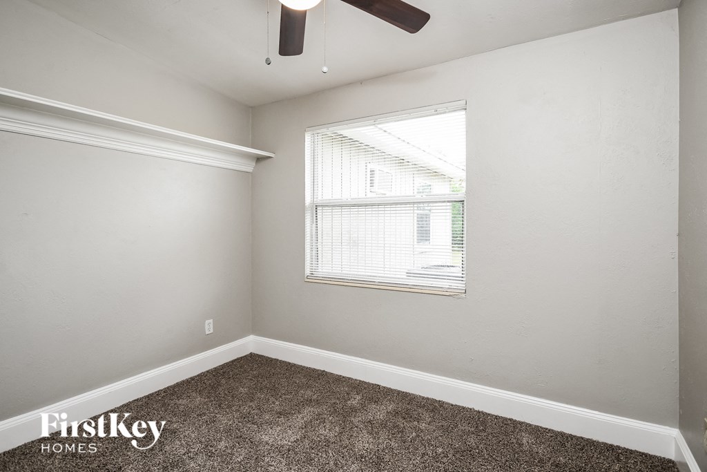 the living room of an apartment with carpet and a window