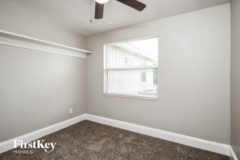 the living room of an apartment with carpet and a window