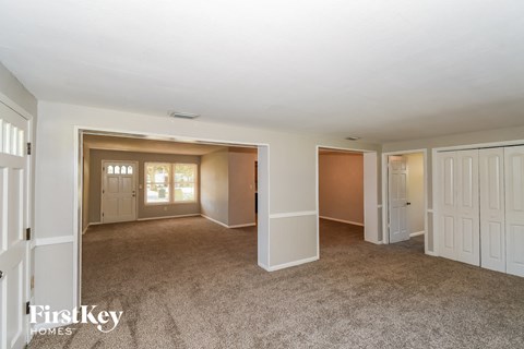 a living room and a dining room with white doors and carpet