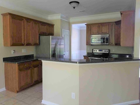 A kitchen with wooden cabinets and a black countertop.