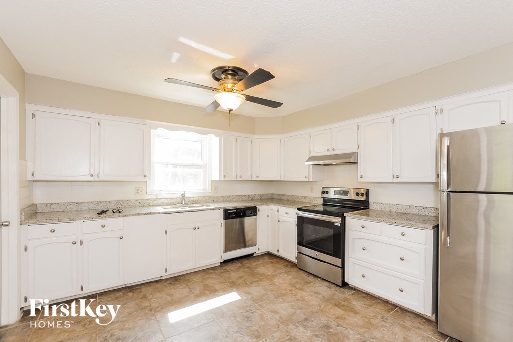 a kitchen with white cabinets and stainless steel appliances and a ceiling fan