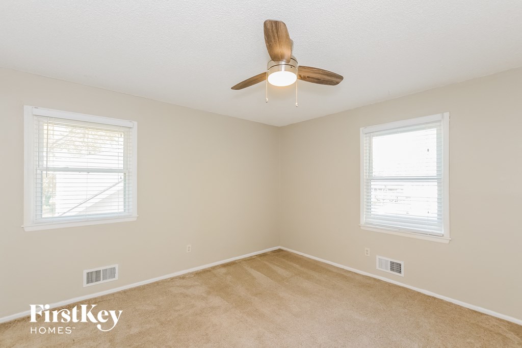 a bedroom with a ceiling fan and two windows