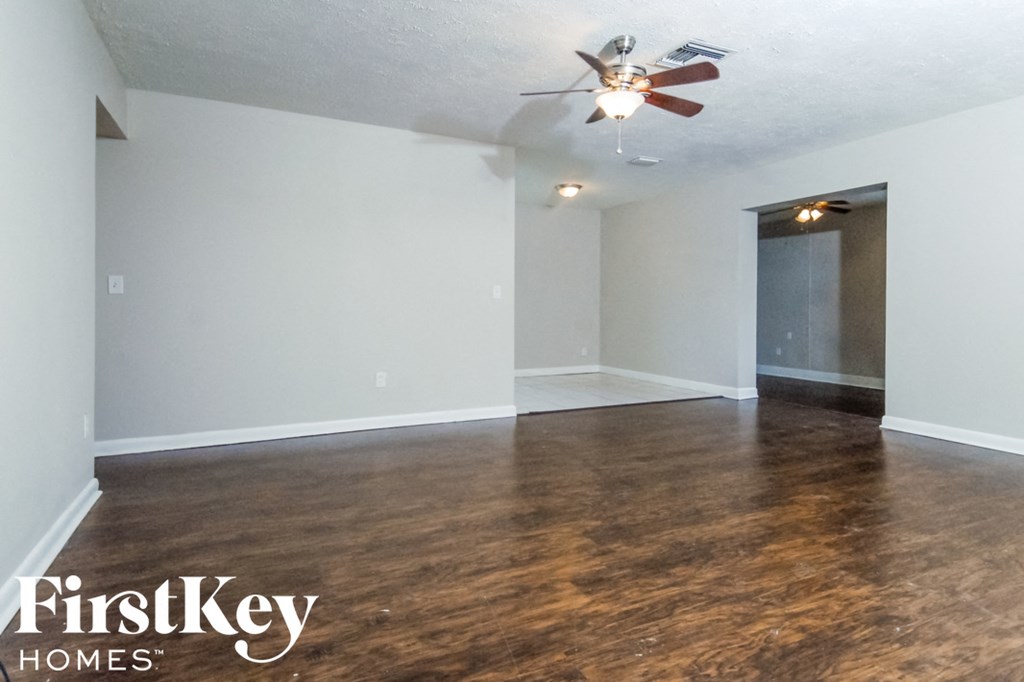 an empty living room with wood flooring and a ceiling fan