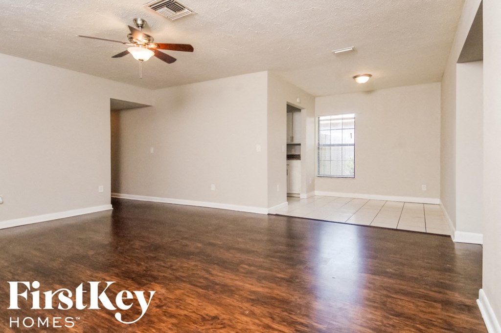 an empty living room with wood flooring and a ceiling fan