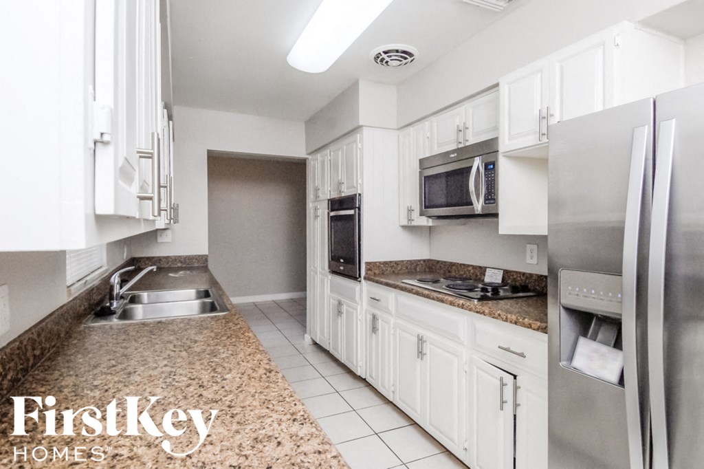 a kitchen with white cabinets and stainless steel appliances and granite counter tops