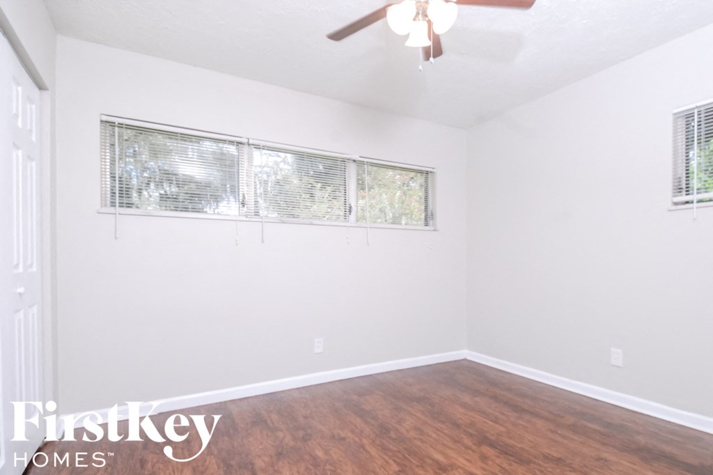 a bedroom with white walls and wood flooring and a window