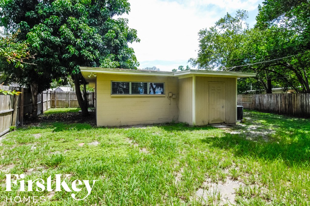 the backyard of a small yellow house with grass and trees