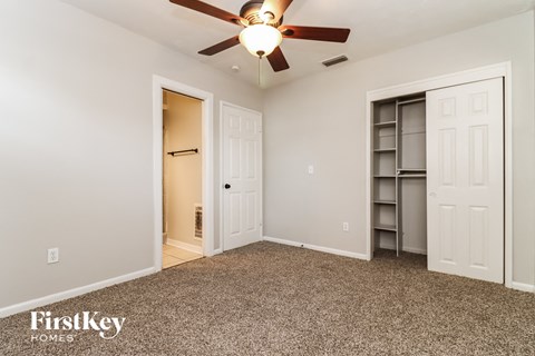 a bedroom with a ceiling fan and a closet