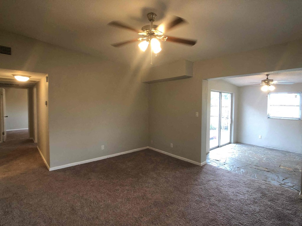 A room with a ceiling fan and carpeted floor.