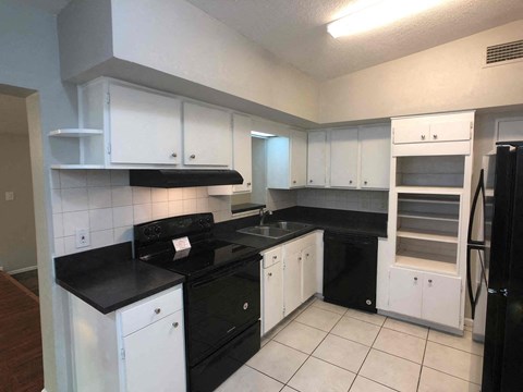 A kitchen with black countertops and white cabinets.
