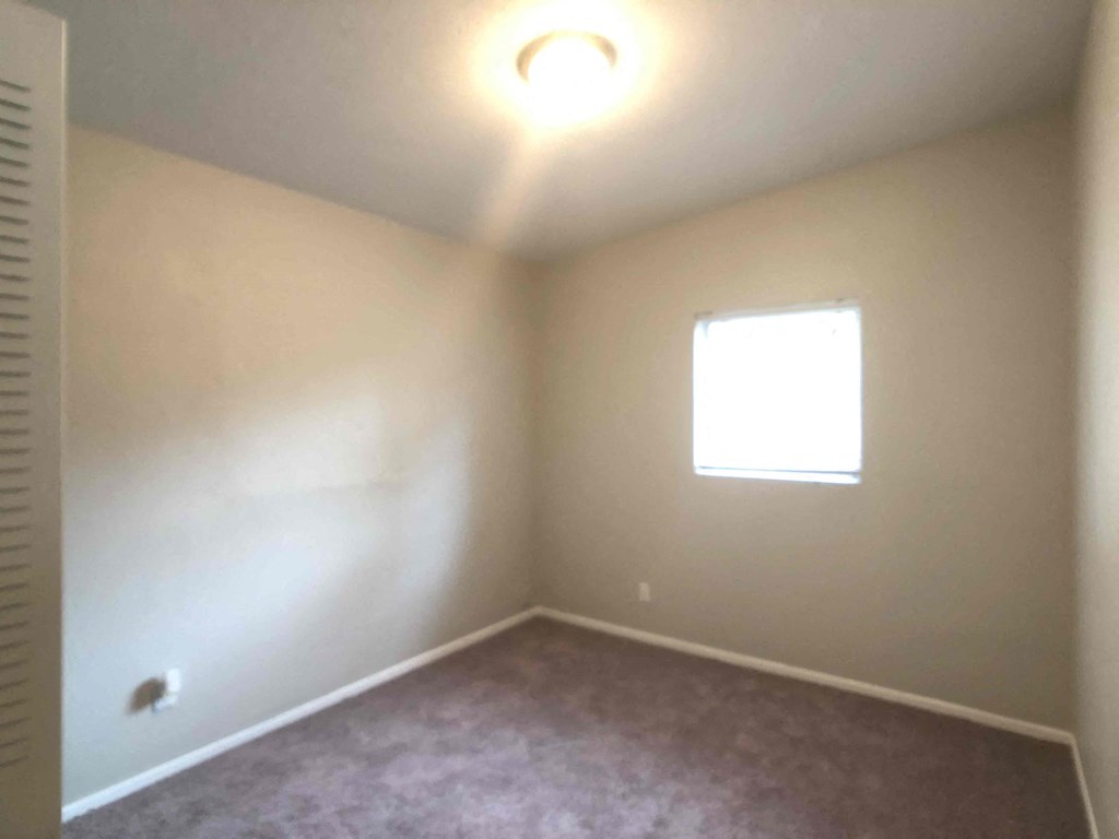 A room with a window and a carpeted floor.