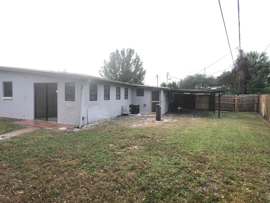 A white building with a black door and windows sits in a grassy area.