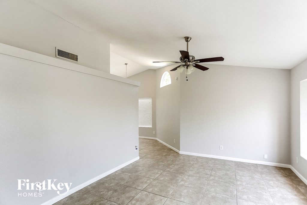 an empty living room with a ceiling fan and a tile floor