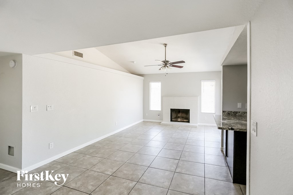 an empty living room with a fireplace and a ceiling fan