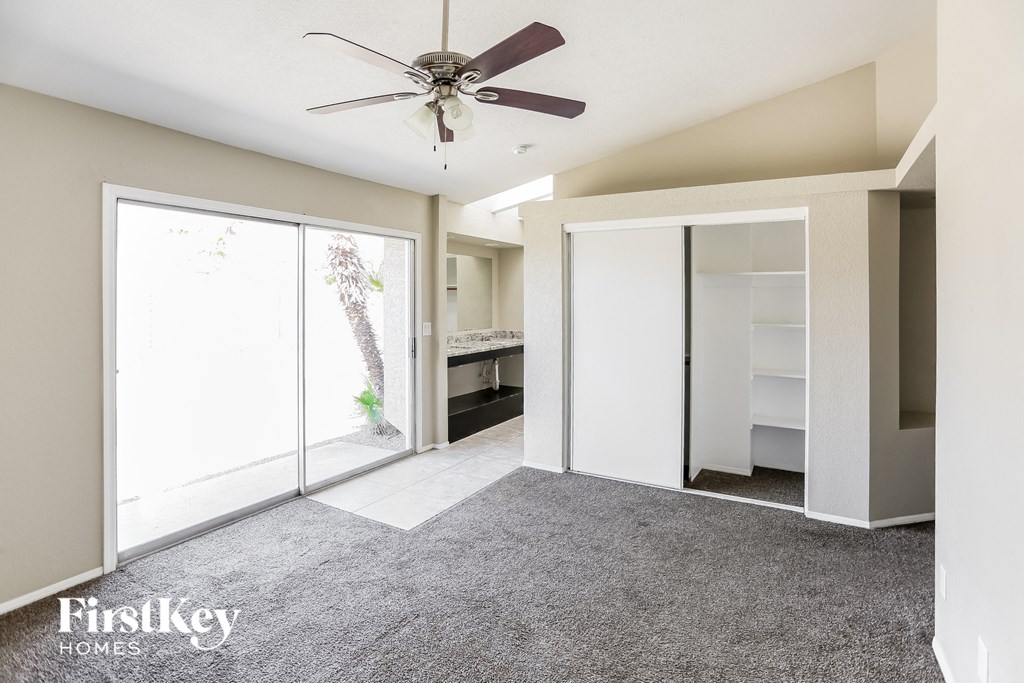 a carpeted living room with a closet and a ceiling fan