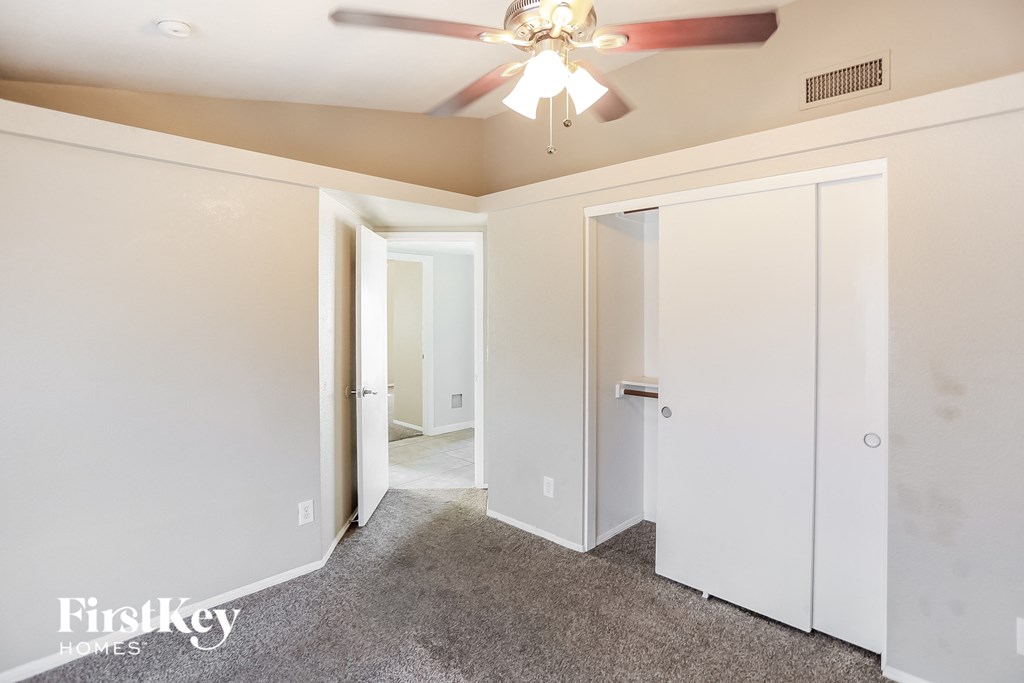 a bedroom with white walls and a ceiling fan