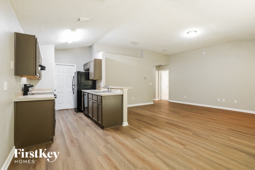 the kitchen and living room of an apartment with wood flooring