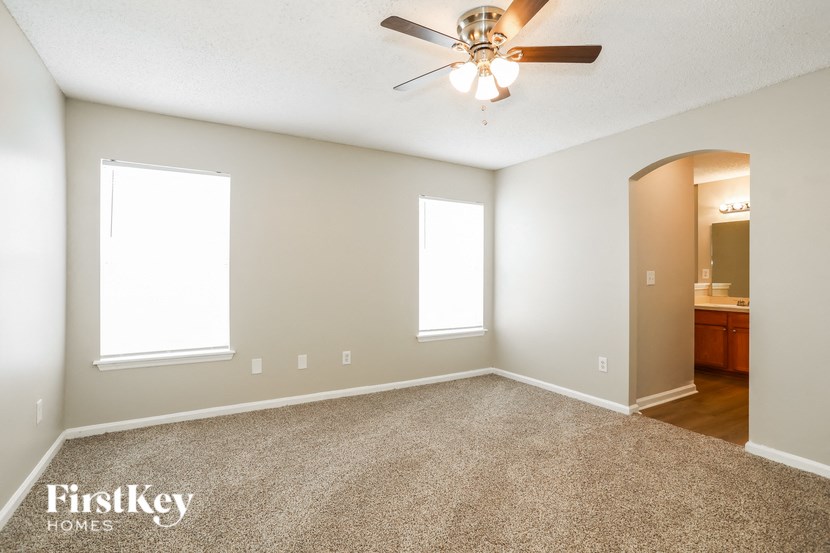 the spacious living room with carpeting and a ceiling fan