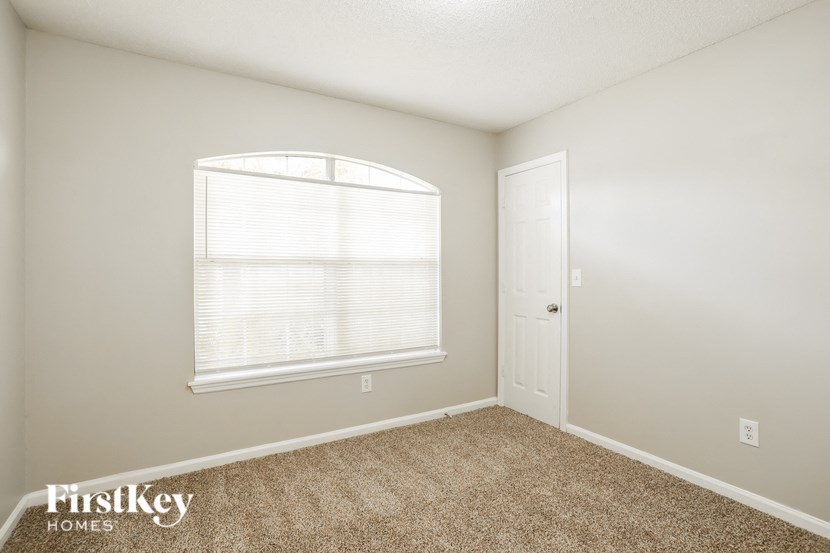 a bedroom with carpet and a large window and a door